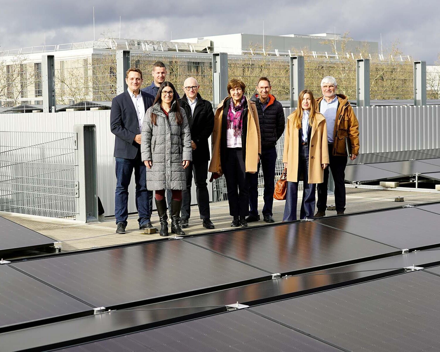 Gruppe von acht Personen steht auf dem Parkhausdach hinter der Solarpanelfläche