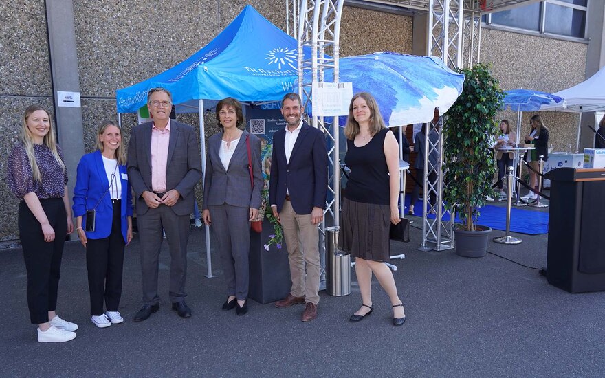 Sechs Personen stehen in einer Reihe vor einem blauen Schirm mit dem Logo der TH Aschaffenburg