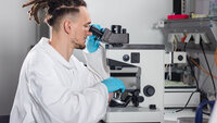A BioMEMS Lab employee looks through a microscope.