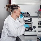 Ein Labormitarbeiter des BioMEMS Lab schaut durch ein Mikroskop.