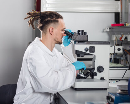 Ein Labormitarbeiter des BioMEMS Lab schaut durch ein Mikroskop.