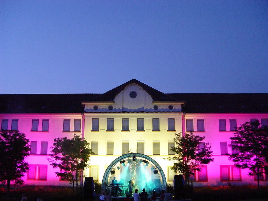 Ein großes Gebäude, dass bei Nacht in bunten Farben beleutet ist.