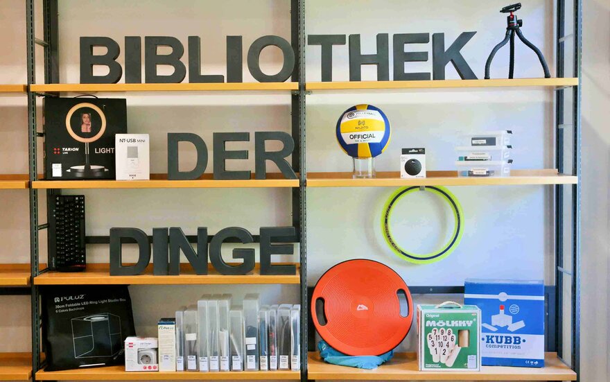 Regale in der Bibliothek gefüllt mit dem Schriftzug - Bibliothek der Dinge - und verschiedenen Gegenständen, die ausgeliehen werden können