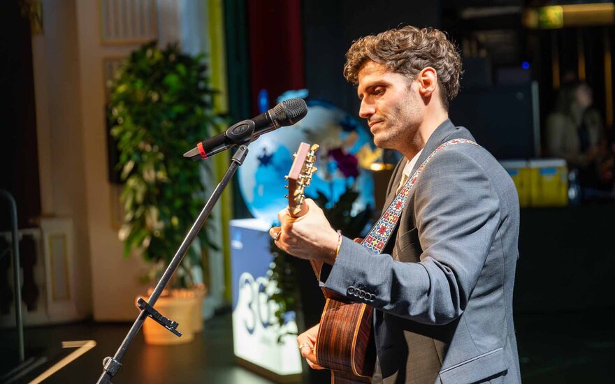 Junger Mann mit Gitarre in der Hand auf der Bühne