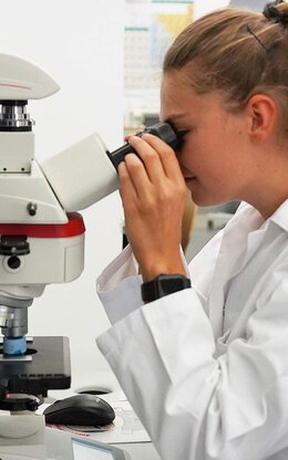 Eine Studentin blickt durch ein Mikroskop.
