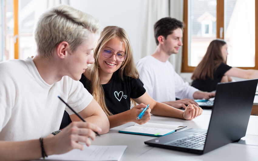 Vier Studierende in Seminarraum mit Laptop