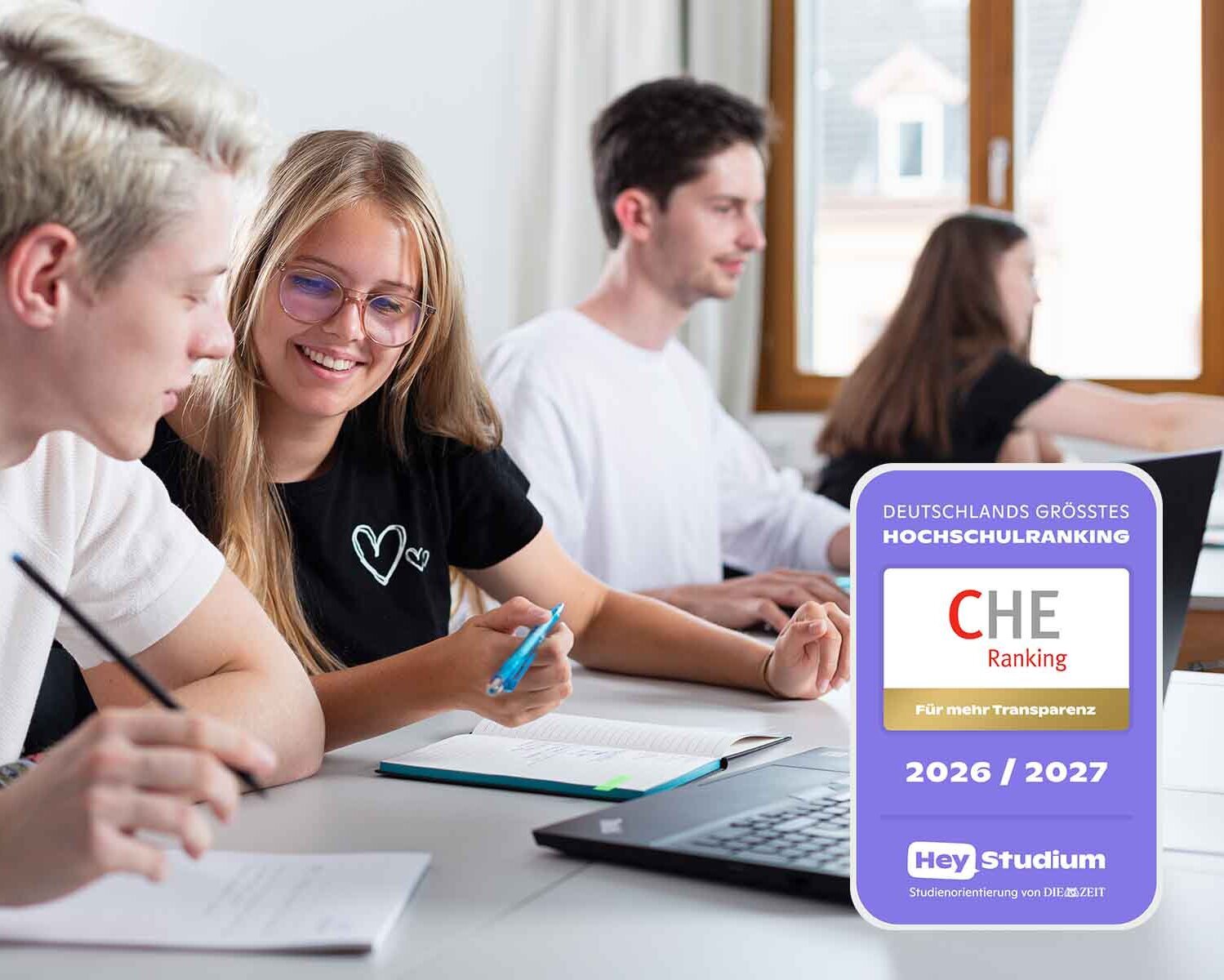 Vier Studierende sitzen vor Laptops an Tischen, Siegel zum Ranking im Vordergrund