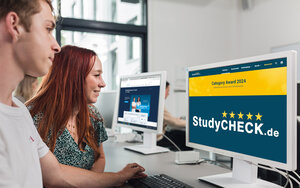 Eine Studentin und ein Student sitzen vor einem Bildschirm, auf dem die Seite von Studycheck mit dem Category Award zu sehen ist.