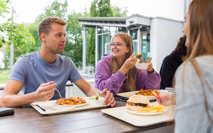 Studierende essen während der Mittagspause im Bereich vor der Mensa
