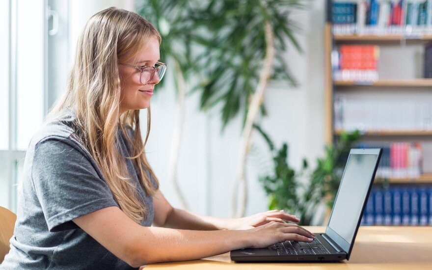 Studentin mit Laptop in der Bibliothek