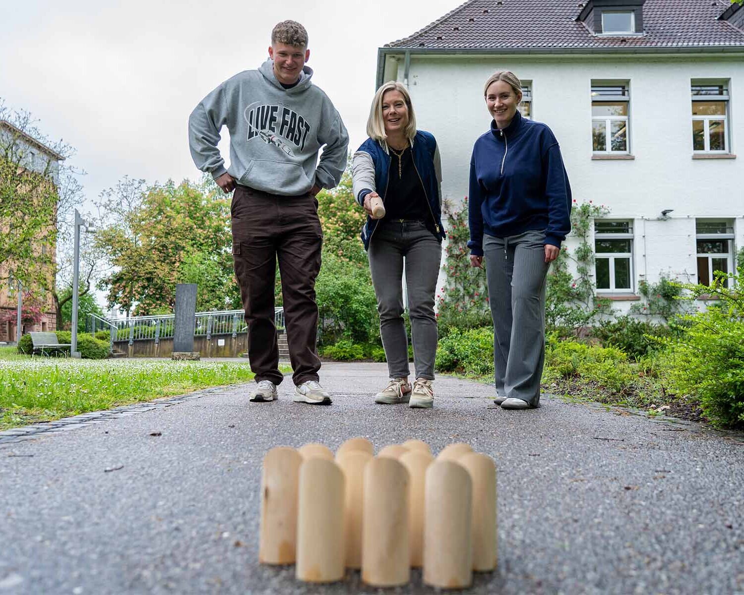 Drei Menschen spielen auf dem Campus ein Spiel.