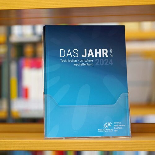 Jahresbericht 2024 mit Frontalansicht des blauen Covers im Bücherregal 