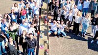 Gruppenfoto der Teilnehmenden am Connection Day mit winkenden Händen auf dem Hof