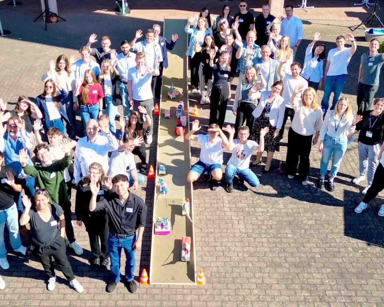 Gruppenfoto der Teilnehmenden am Connection Day mit winkenden Händen auf dem Hof