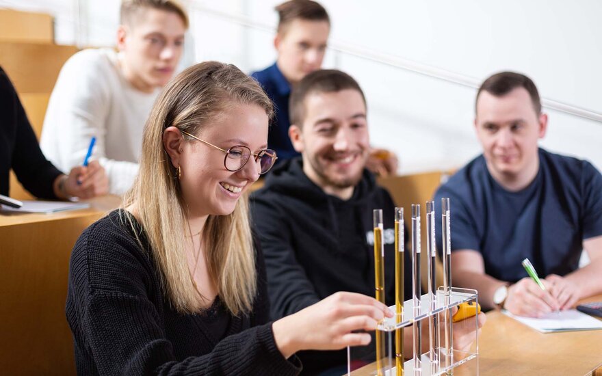 Studierende arbeiten während einer Vorlesung mit chemischen Flüssigkeiten in Reagenzgläsern