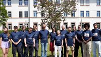 Laufteam der TH AB mit blauen T-Shirts auf Campuswiese vor weißem Gebäude 20