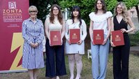 Zonta-Präsidentin mit den vier Preisträgerinnen mit Urkunden in der Hand vor Zonta-Roll-up