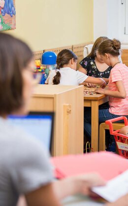 Eltern-Kind-Carell in der Bibliothek, zwei Studentinnen lernen und die Kinder spielen