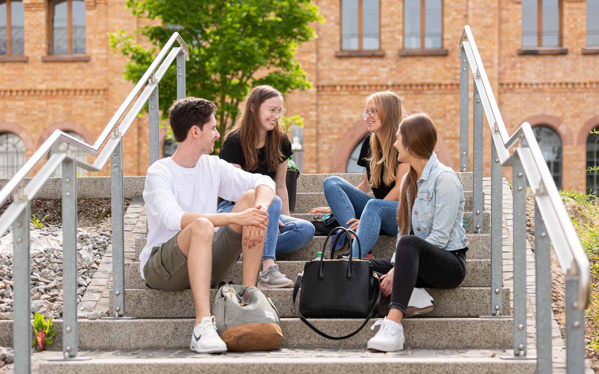 Studierende auf einer Treppe auf dem Campus-Gelände