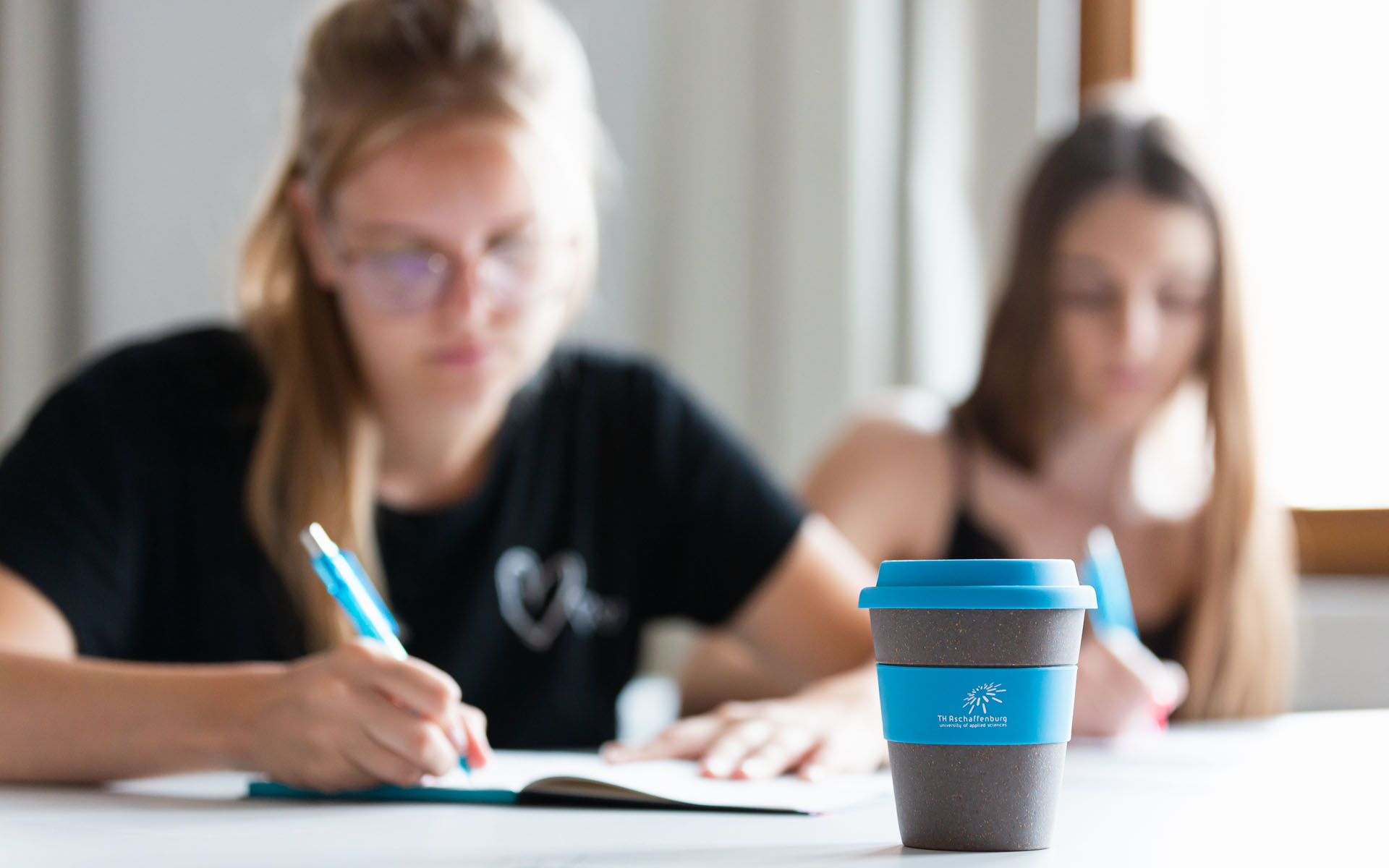 Zwei Studentinnen beim Lernen mit TH AB To-Go Kaffeebecher 