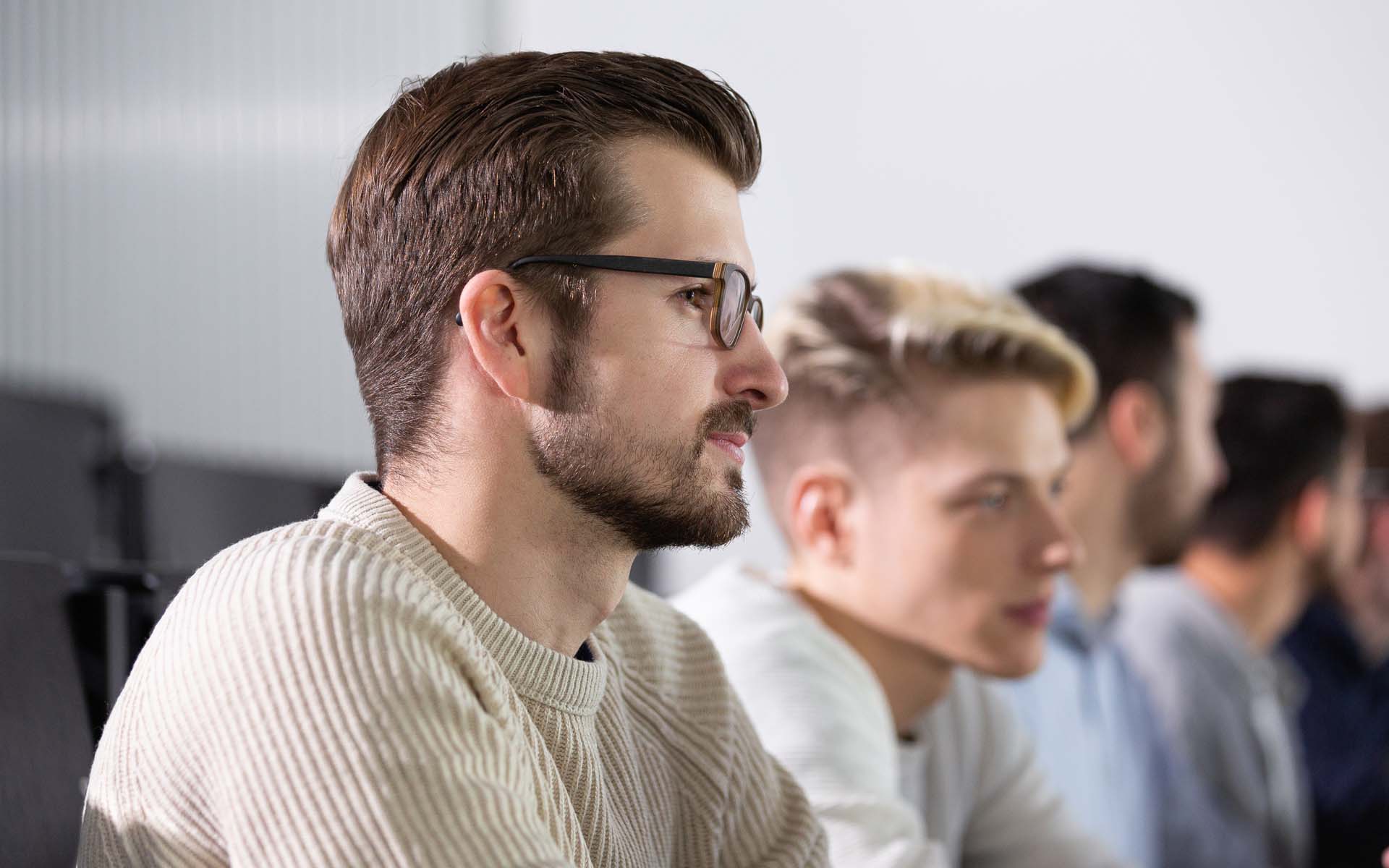 Mehrere Studierende in einer Sitzreihe während einer Vorlesung in einem Hörssal im Gebäude 40