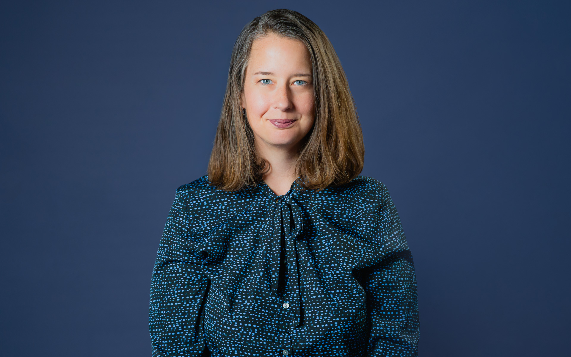Portrait von Eva Heberer, Mitarbeiterin der TH Aschaffenburg vor einem dunkelblauen Hintergrund