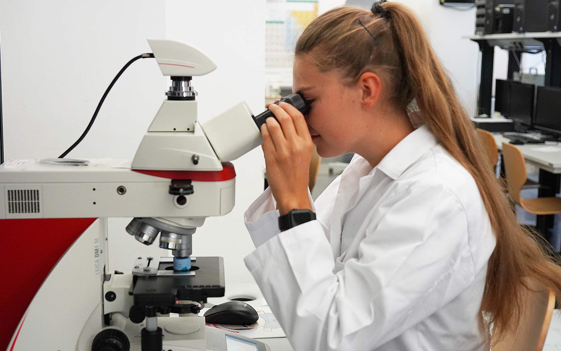 Eine Studentin blickt durch ein Mikroskop.