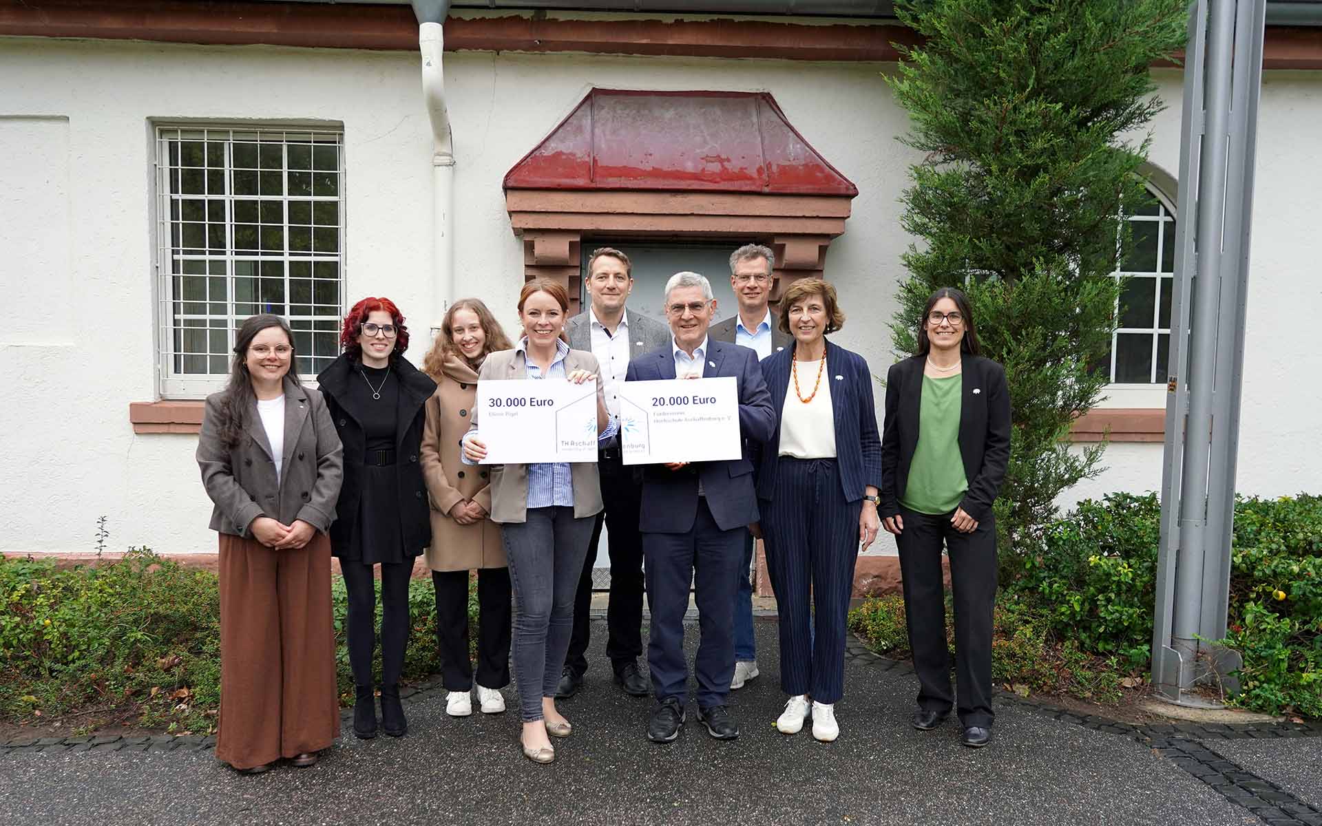 Gruppenbild mit 9 Personen (Spender, Hochschulleitung und Studierende) vor Gebäude 21